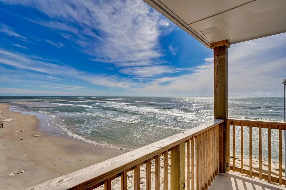 The hero image shows a stunning third-floor view of the ocean, with gentle waves rolling onto a wide, sandy beach under a clear blue sky. The scene evokes relaxation and adventure, with the beach stretching as far as the eye can see—perfect for sunbathing, beachcombing, or simply soaking in the sunrise from a private balcony.